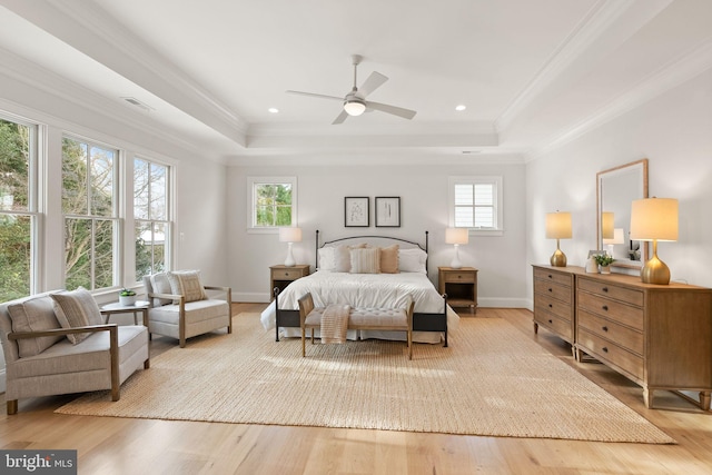 bedroom with light hardwood / wood-style floors, a raised ceiling, and ceiling fan