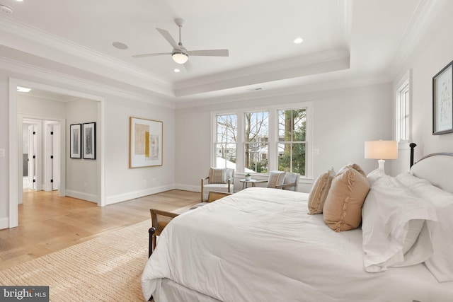 bedroom with light wood-type flooring, a tray ceiling, ceiling fan, and crown molding