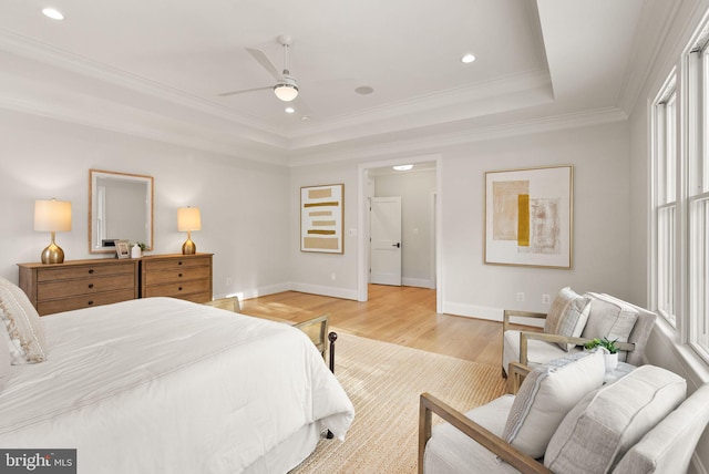 bedroom featuring light wood-type flooring, a raised ceiling, ceiling fan, crown molding, and multiple windows