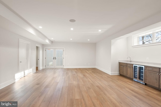 bar featuring french doors, beverage cooler, and light wood-type flooring