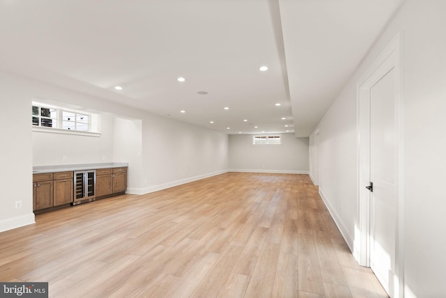 basement featuring a wall mounted air conditioner, indoor bar, wine cooler, and light hardwood / wood-style flooring