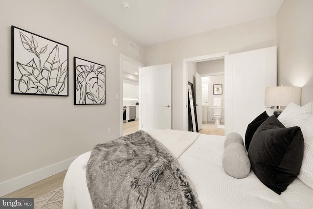 bedroom featuring light wood-type flooring and ensuite bathroom