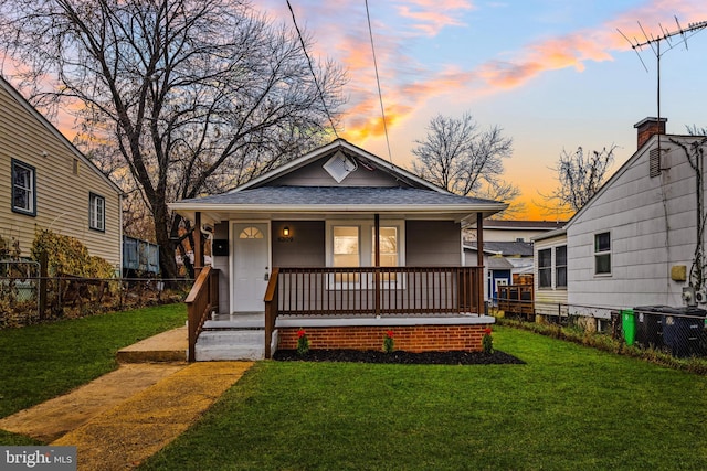 bungalow-style house with a porch, a yard, and central AC