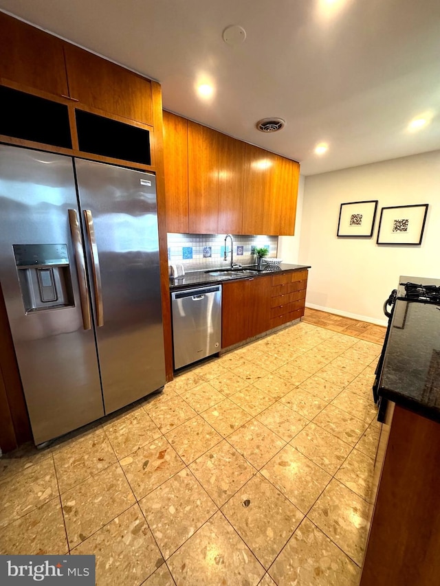 2201 L St NW Unit 906, Washington, DC 20037 - kitchen featuring stainless steel appliances, brown cabinets, tasteful backsplash, a sink, and light tile patterned floors