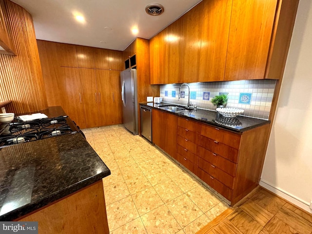 2201 L St NW Unit 906, Washington, DC 20037 - kitchen with appliances with stainless steel finishes, a sink, brown cabinets, backsplash, and dark stone counters