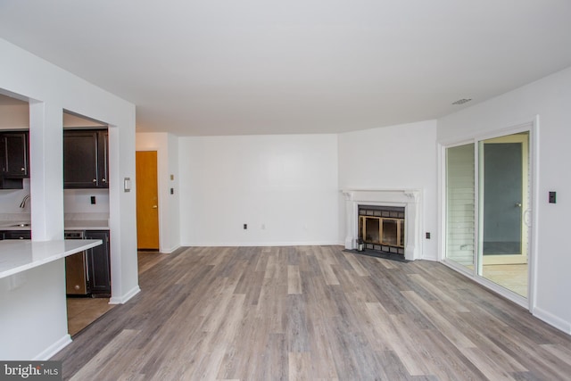 unfurnished living room featuring sink, wine cooler, and light hardwood / wood-style flooring