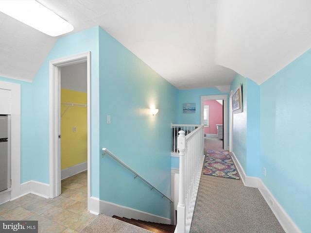 corridor featuring light colored carpet and vaulted ceiling