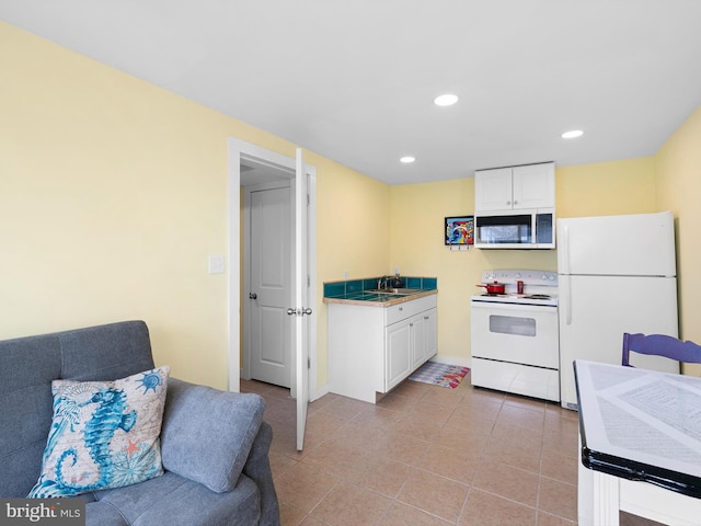 kitchen with white cabinets, white appliances, sink, and light tile patterned floors