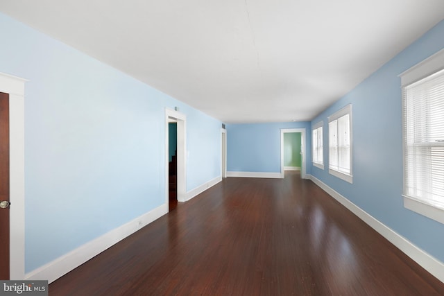 empty room with dark wood-type flooring and a wealth of natural light