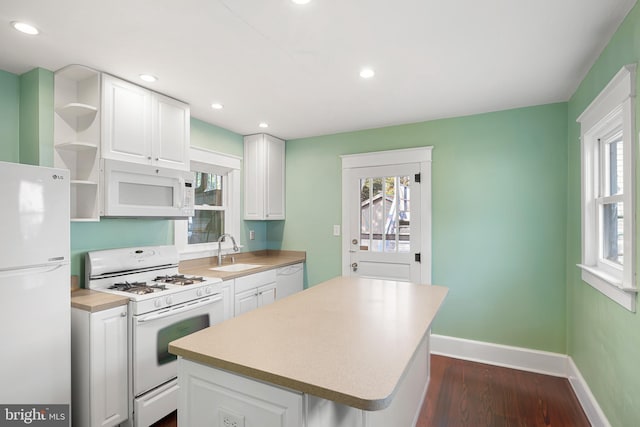 kitchen featuring dark hardwood / wood-style flooring, white appliances, sink, white cabinets, and a kitchen island