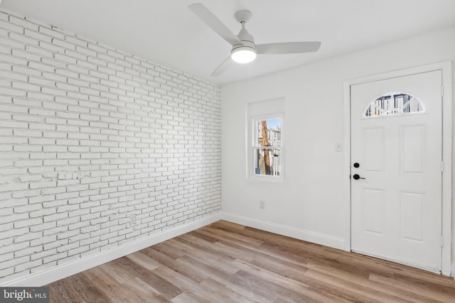 entrance foyer featuring ceiling fan, brick wall, and light hardwood / wood-style flooring