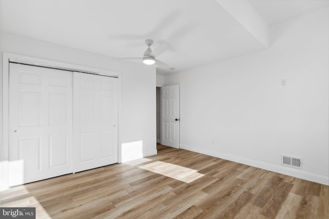 unfurnished bedroom featuring ceiling fan, a closet, and light wood-type flooring