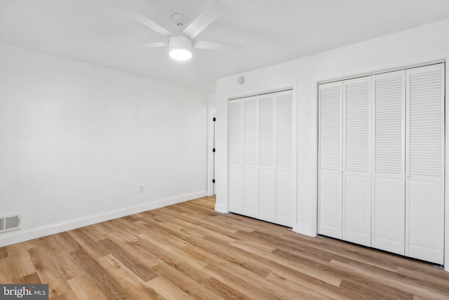 unfurnished bedroom featuring ceiling fan, light hardwood / wood-style floors, and two closets