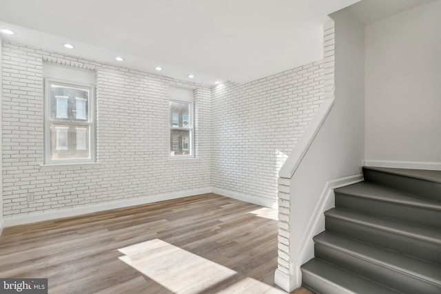 staircase featuring hardwood / wood-style floors and brick wall