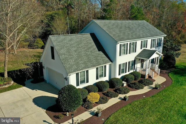 colonial-style house with covered porch, a garage, and a front yard