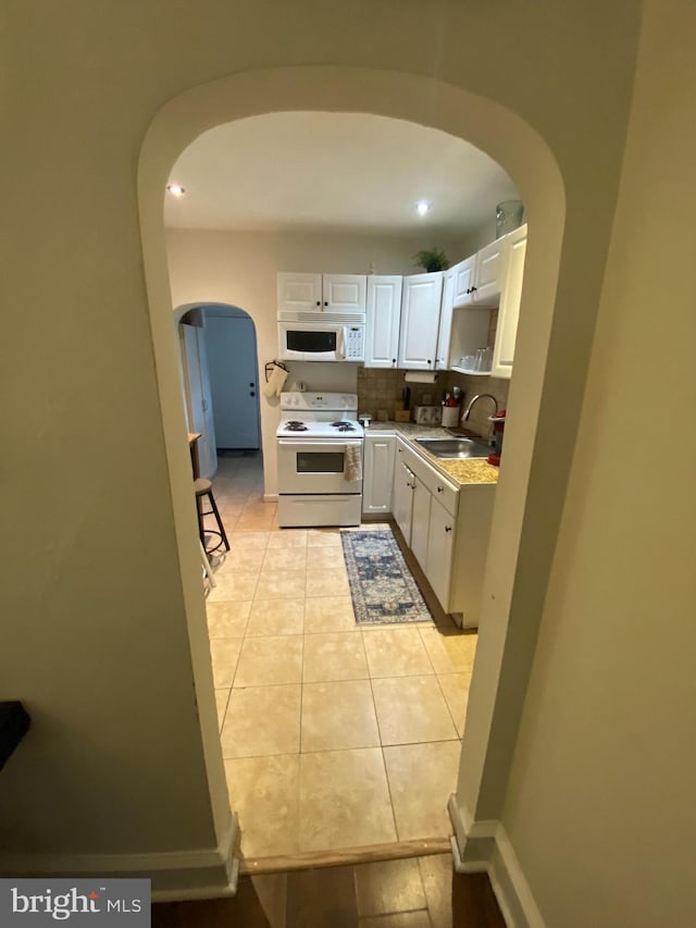 kitchen with white appliances, white cabinets, sink, tasteful backsplash, and light tile patterned flooring