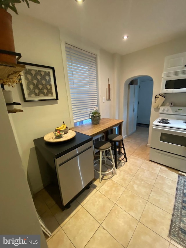 kitchen with white cabinets, white appliances, and light tile patterned flooring