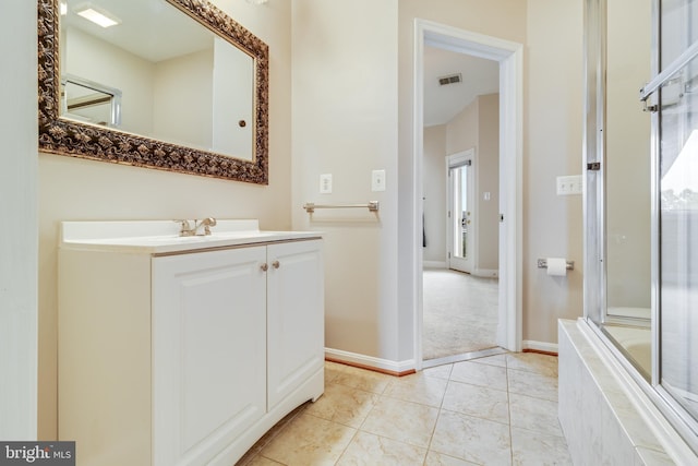 bathroom featuring a relaxing tiled tub, vanity, a healthy amount of sunlight, and tile patterned floors