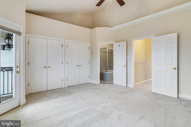 unfurnished bedroom with light carpet, two closets, ceiling fan, high vaulted ceiling, and connected bathroom