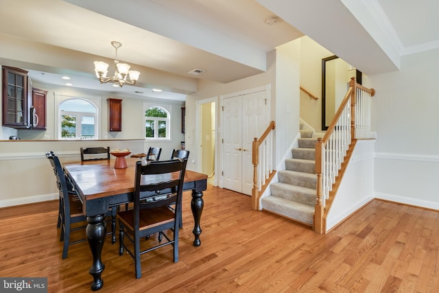 dining space with a notable chandelier, light wood-type flooring, and crown molding