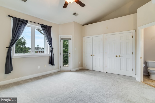 unfurnished bedroom with ensuite bathroom, ceiling fan, light colored carpet, and vaulted ceiling