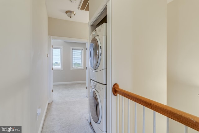 laundry area featuring stacked washer / dryer and light colored carpet