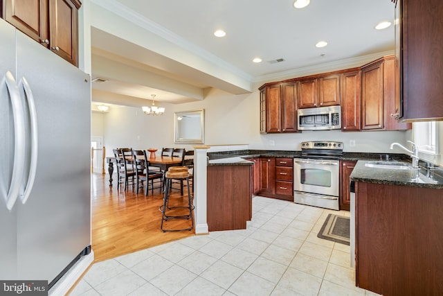 kitchen featuring ornamental molding, stainless steel appliances, light hardwood / wood-style flooring, a notable chandelier, and hanging light fixtures