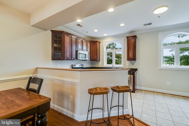 kitchen with electric stove, sink, crown molding, light tile patterned flooring, and kitchen peninsula