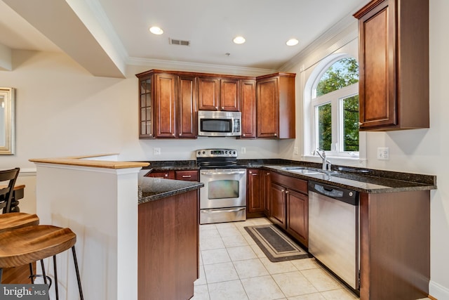 kitchen featuring kitchen peninsula, appliances with stainless steel finishes, crown molding, sink, and light tile patterned flooring