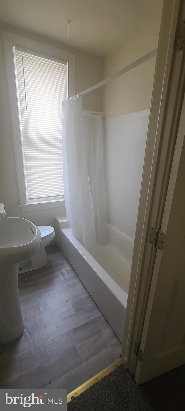 bathroom featuring hardwood / wood-style floors, shower / bath combo, and toilet