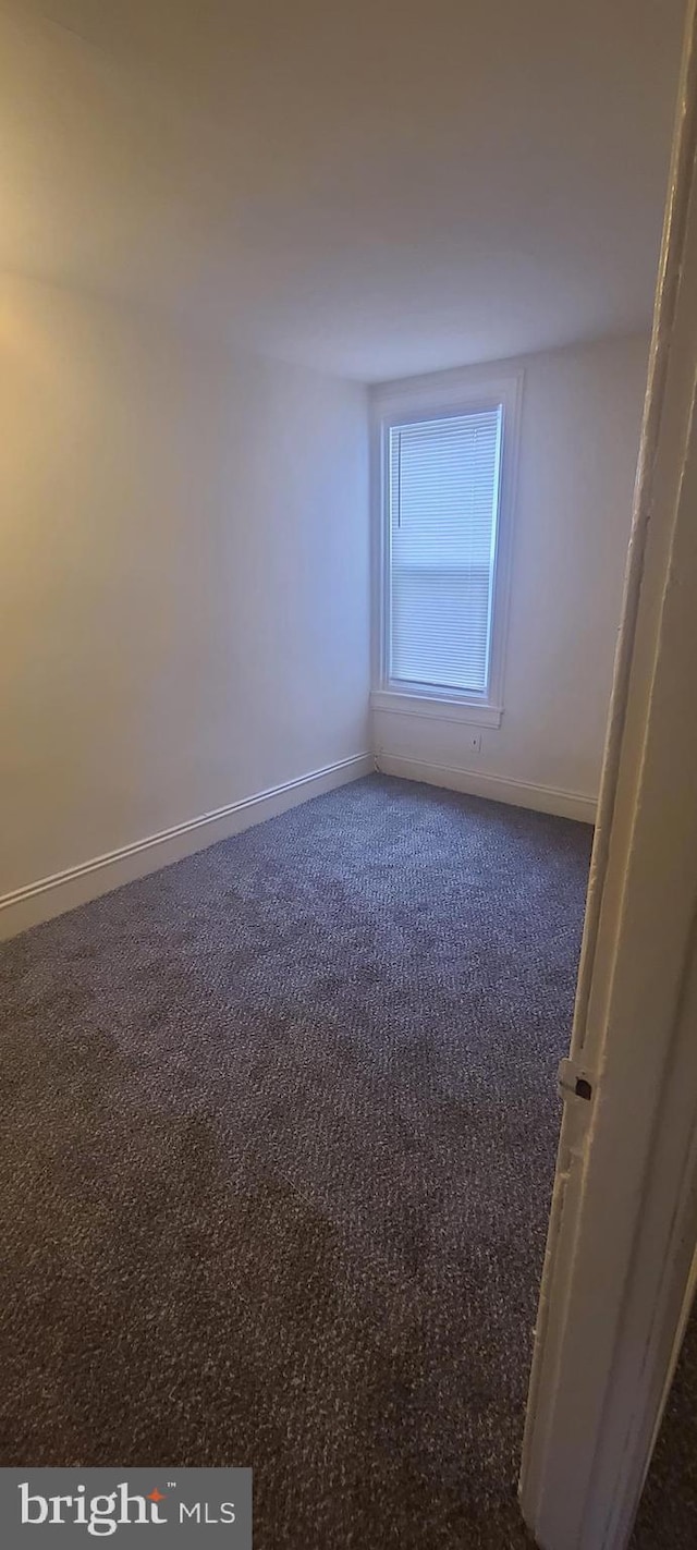 spare room with dark carpet