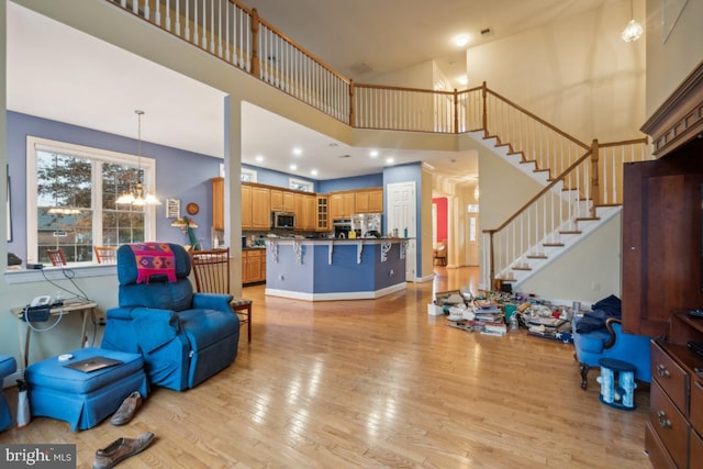 living room featuring a chandelier, a high ceiling, and light wood-type flooring