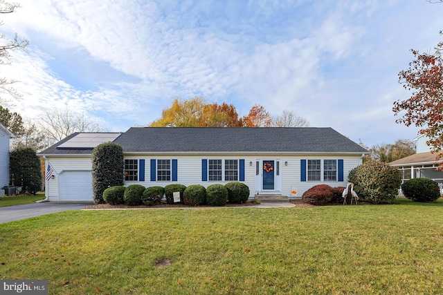 ranch-style house with a front yard, solar panels, and a garage