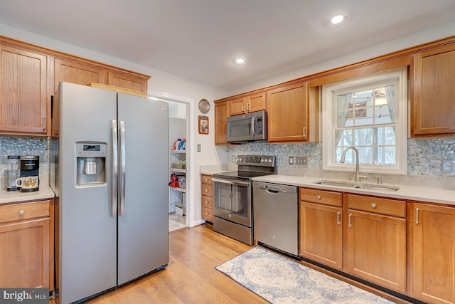 kitchen with decorative backsplash, light hardwood / wood-style floors, sink, and stainless steel appliances