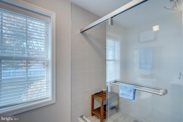 bathroom with a wealth of natural light and a shower with shower door