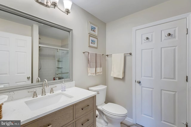 bathroom featuring a shower with door, vanity, and toilet