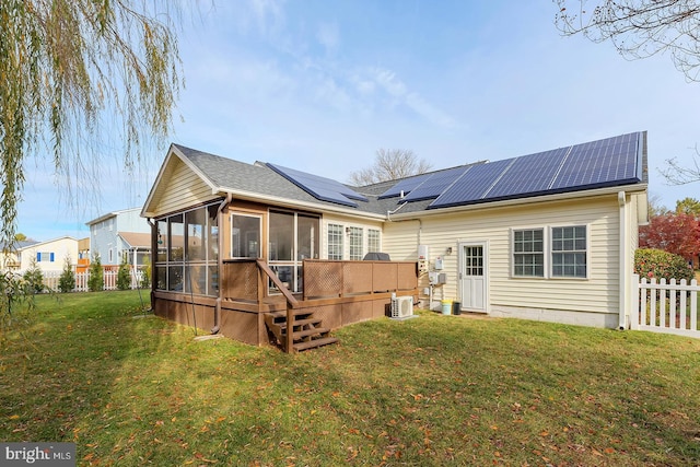 rear view of house with solar panels, a yard, cooling unit, and a sunroom