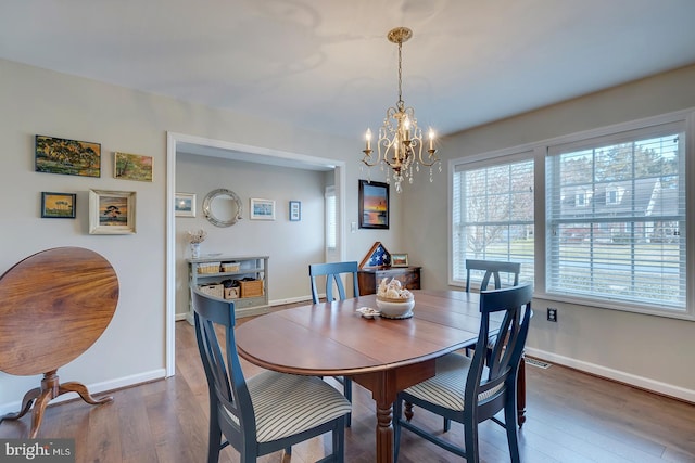 dining area with dark hardwood / wood-style floors and a notable chandelier