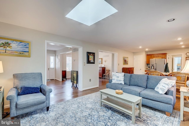 living room with dark hardwood / wood-style flooring and a skylight