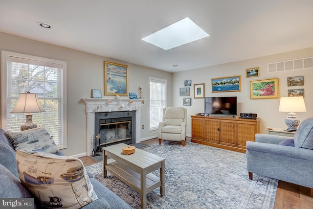 living room with light wood-type flooring and a skylight