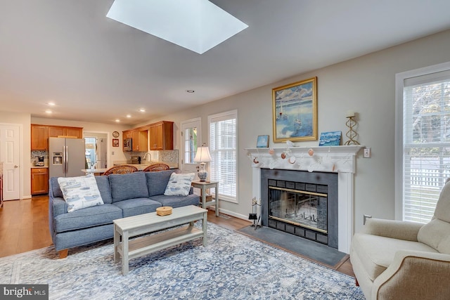 living room featuring a skylight, plenty of natural light, and light hardwood / wood-style floors