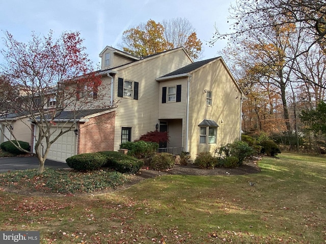 view of front of property with brick siding, driveway, an attached garage, and a front yard