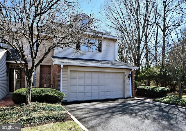 view of front of house featuring aphalt driveway, an attached garage, and brick siding