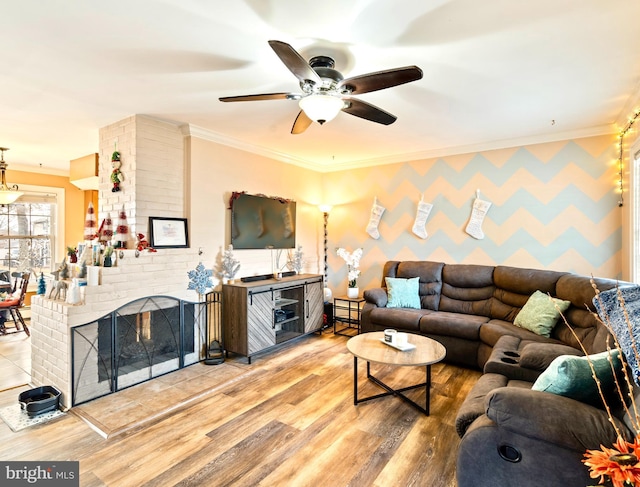 living room featuring ceiling fan, a brick fireplace, ornamental molding, and hardwood / wood-style flooring