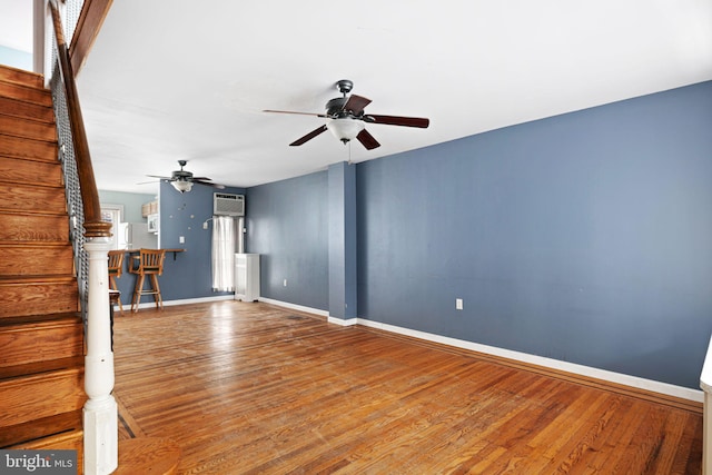 unfurnished living room featuring ceiling fan, wood-type flooring, and a wall mounted AC