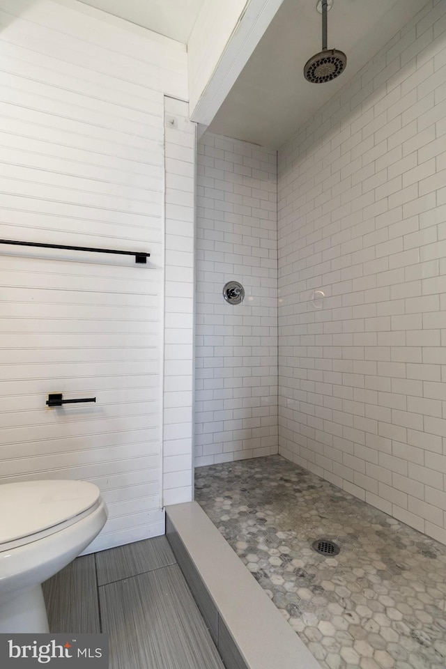 bathroom with tiled shower, tile patterned flooring, and toilet