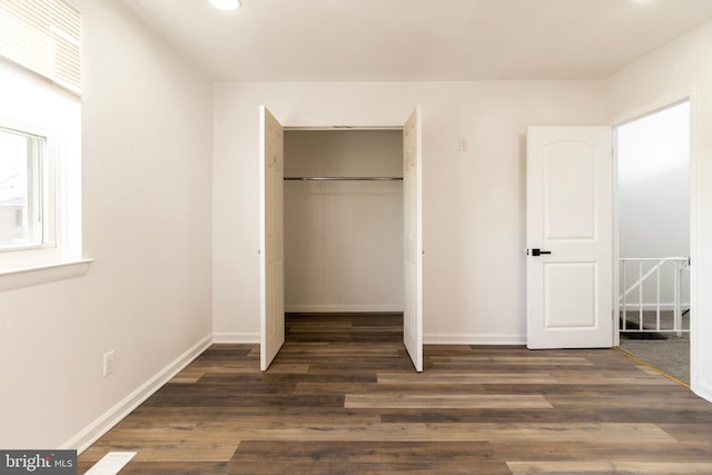 unfurnished bedroom with dark wood-type flooring and a closet