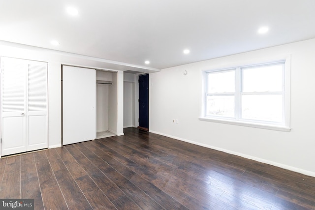 unfurnished bedroom featuring multiple closets and dark wood-type flooring