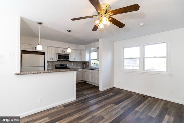 kitchen featuring white cabinetry, hanging light fixtures, dark hardwood / wood-style floors, kitchen peninsula, and appliances with stainless steel finishes