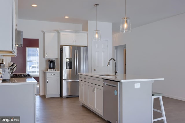 kitchen featuring white cabinetry, sink, wood-type flooring, a center island with sink, and appliances with stainless steel finishes